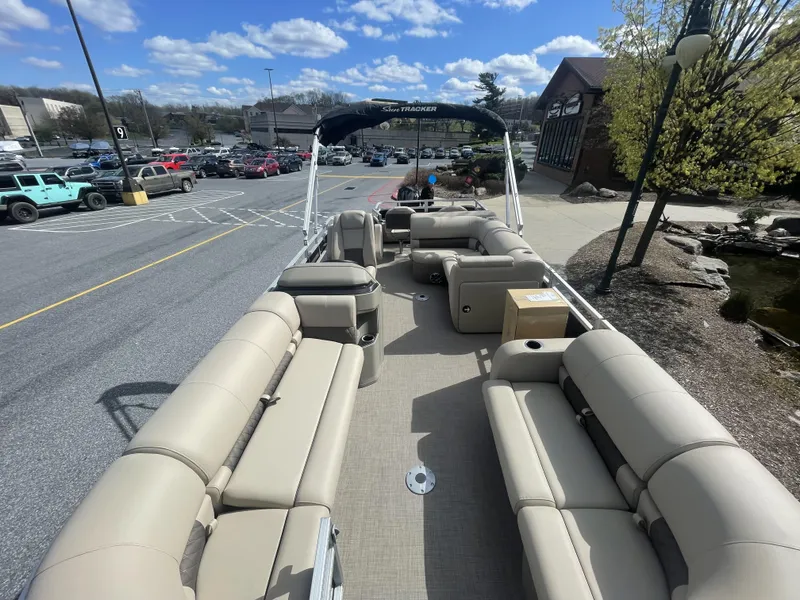 Slide: The Image of 2025 Sun Tracker SportFish 22 DLX pontoon boat with beige seating, parked outdoors. - 2