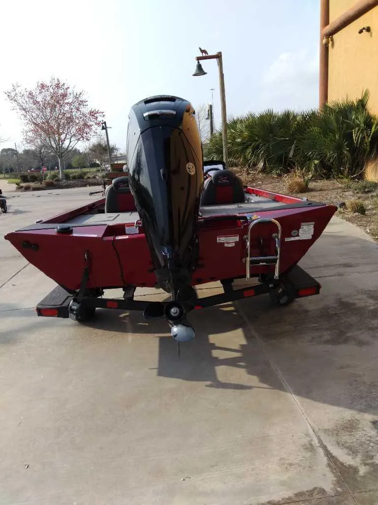 Slide: The Image of 2025 Ranger RT178 boat, red, parked outdoors, rear view with motor and trailer. - 7