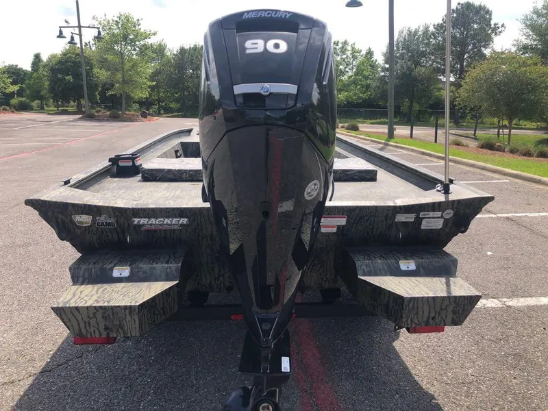 Slide: The Image of 2025 Tracker Grizzly 1860 CC boat with Mercury 90 engine in a parking lot. - 2