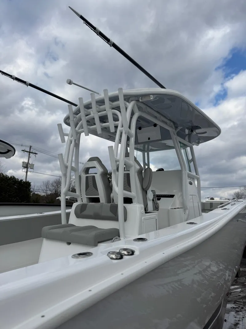 Slide: The Image of 2025 Cape Horn 34 XS boat with sleek design and fishing rod holders under cloudy sky. - 14