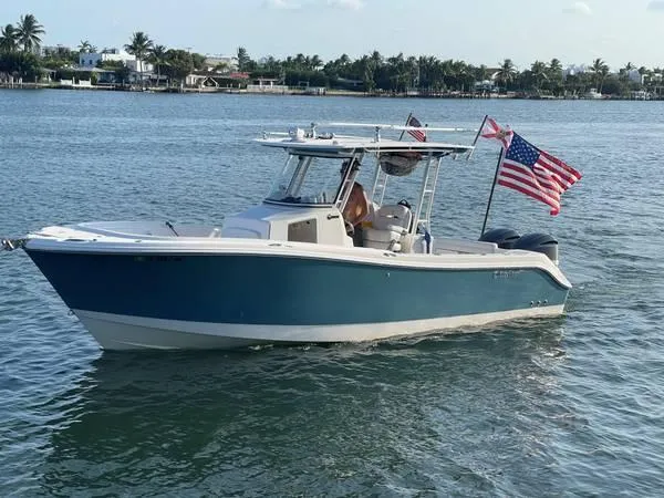 The Image of 2015 Edgewater 280CC boat on water with American flag, clear sky, and distant shoreline. - 0