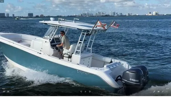 Slide: The Image of 2015 Edgewater 280CC boat cruising on open water with city skyline in background. - 1