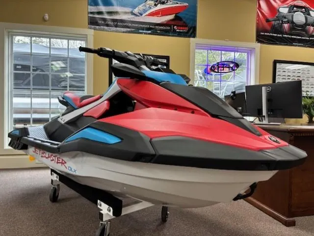 The Image of 2025 Yamaha WaveRunner JetBlaster DLX 3-Up in showroom, vibrant red and black design. - 0