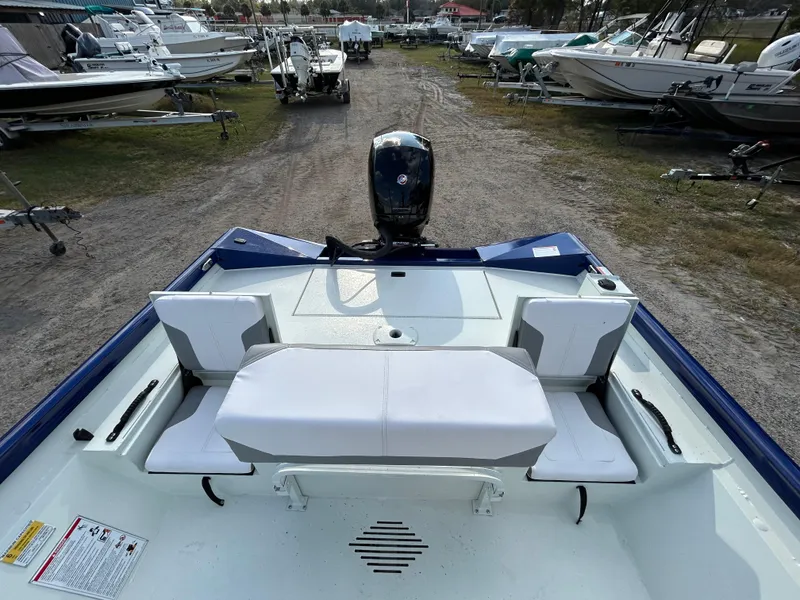 Slide: The Image of 2025 Crestliner 2000 Bay boat interior with seating and motor, parked among other boats. - 19