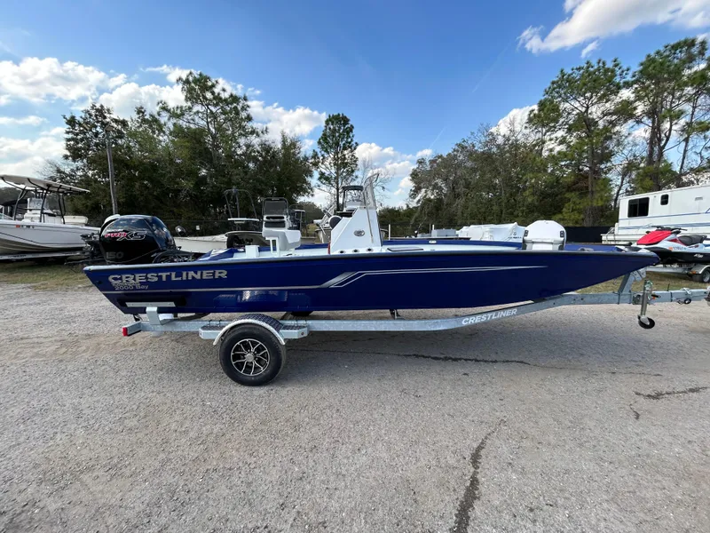 Slide: The Image of 2025 Crestliner 2000 Bay boat on trailer, parked outdoors under a blue sky. - 6