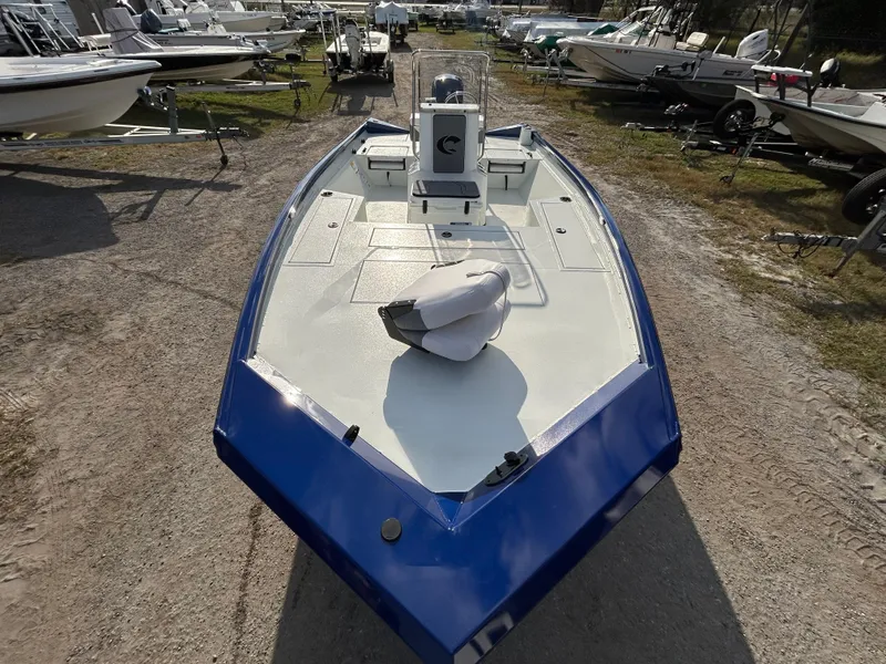 Slide: The Image of 2025 Crestliner 2000 Bay boat, blue and white, parked on a gravel lot with other boats. - 9