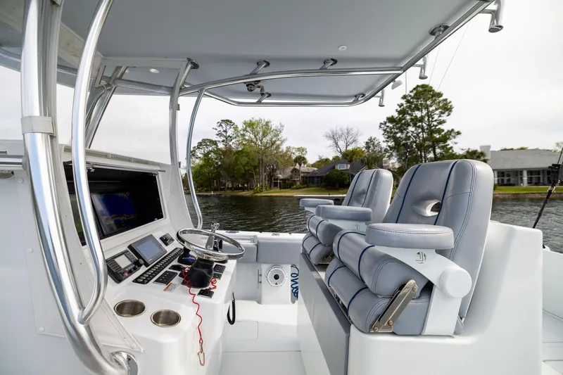 Slide: The Image of 2022 Contender 35ST boat interior with dual seats and control panel, docked by a scenic shoreline. - 41