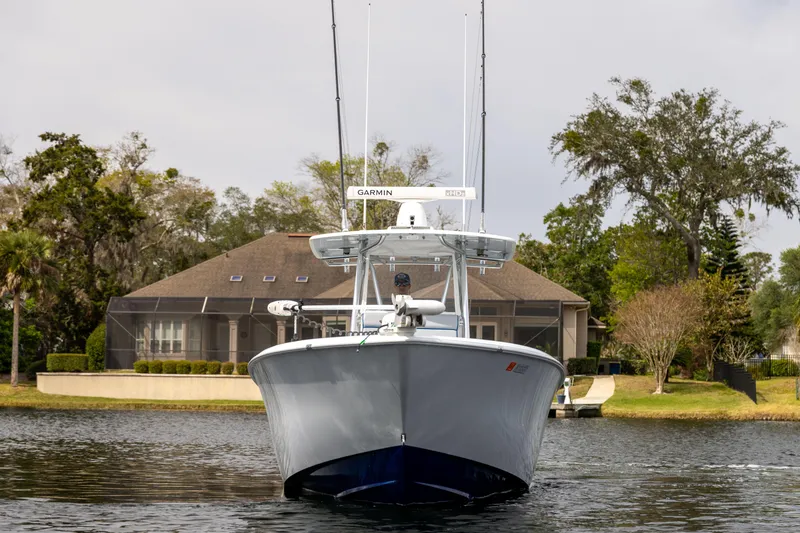Slide: The Image of 2022 Contender 35ST boat on water, front view, with house and trees in background. - 6