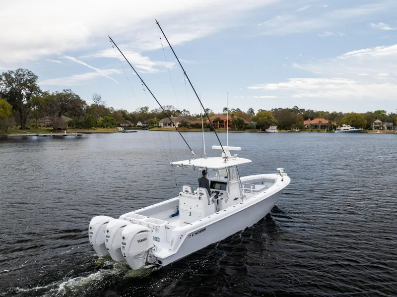 Slide: The Image of 2022 Contender 35ST boat cruising on a calm lake with dual outboard engines. - 9