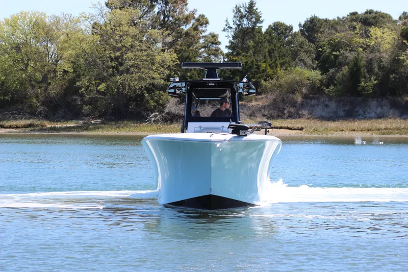 Slide: The Image of 2024 Front Runner 33 Center Console boat cruising on a serene lake with lush greenery. - 7