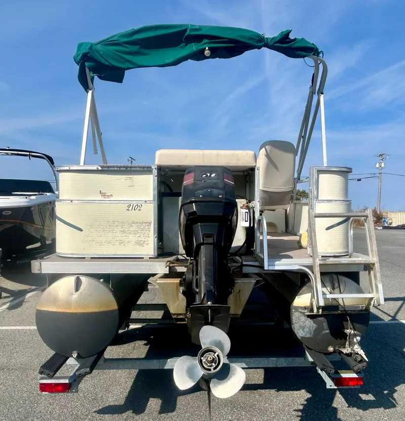 Slide: The Image of 2003 Odyssey Pontoons 2101 Millennium with canopy and outboard motor, parked on a trailer. - 15