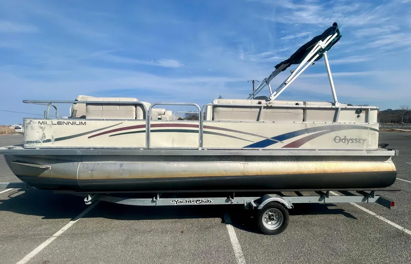 Slide: The Image of 2003 Odyssey Pontoons 2101 Millennium boat on trailer, parked in a lot under clear skies. - 4