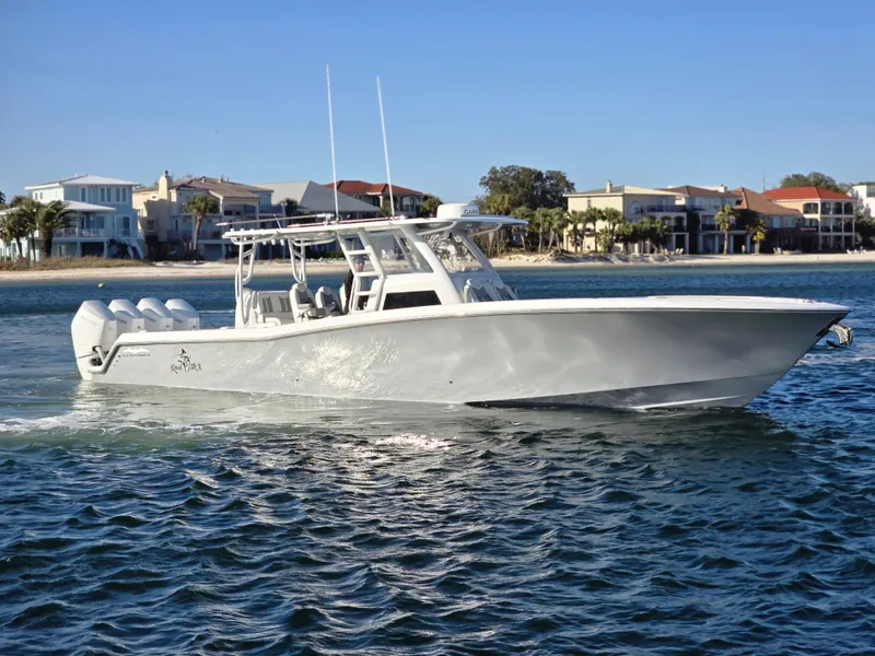 The Image of 2024 Invincible 43 Open Fisherman boat cruising near a coastal residential area. - 0