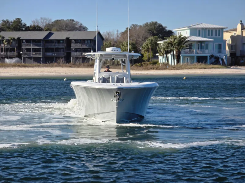 Slide: The Image of 2024 Invincible 43 Open Fisherman boat cruising near a sandy beach with waterfront homes. - 25