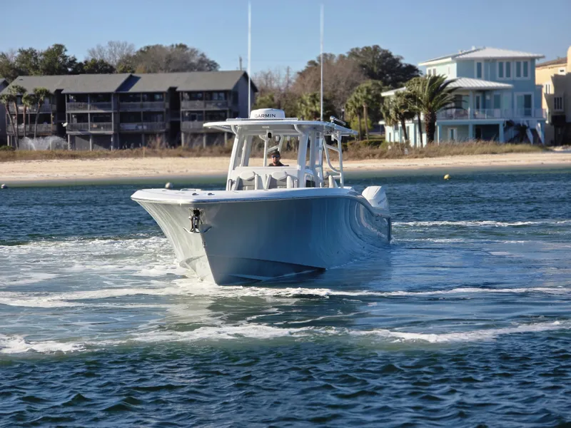 Slide: The Image of 2024 Invincible 43 Open Fisherman boat cruising near a sandy shoreline. - 26