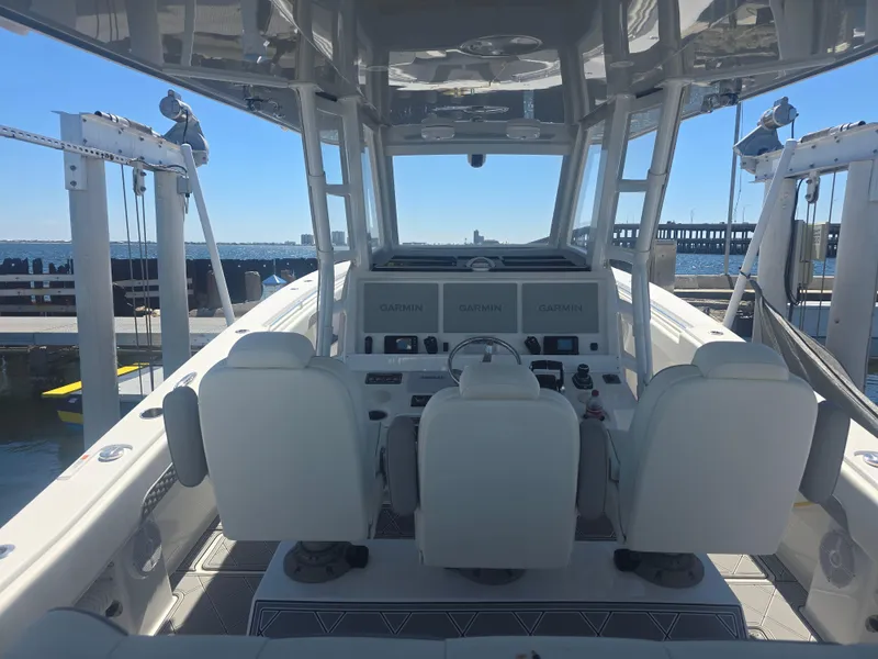 Slide: The Image of 2024 Invincible 43 Open Fisherman boat interior with helm and seating, docked by the water. - 9