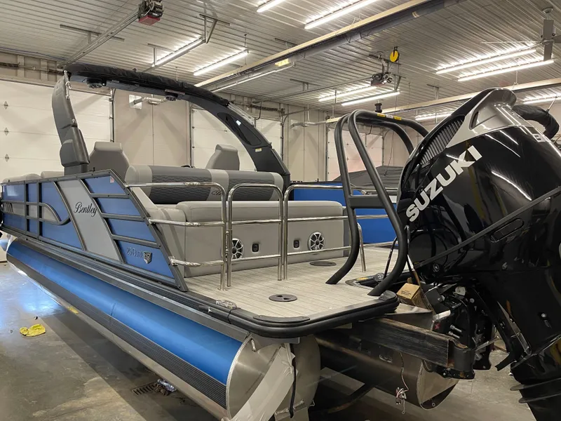 Slide: The Image of 2025 Bentley Pontoons Elite 253 Swingback Tower in a garage, featuring a Suzuki outboard motor. - 4