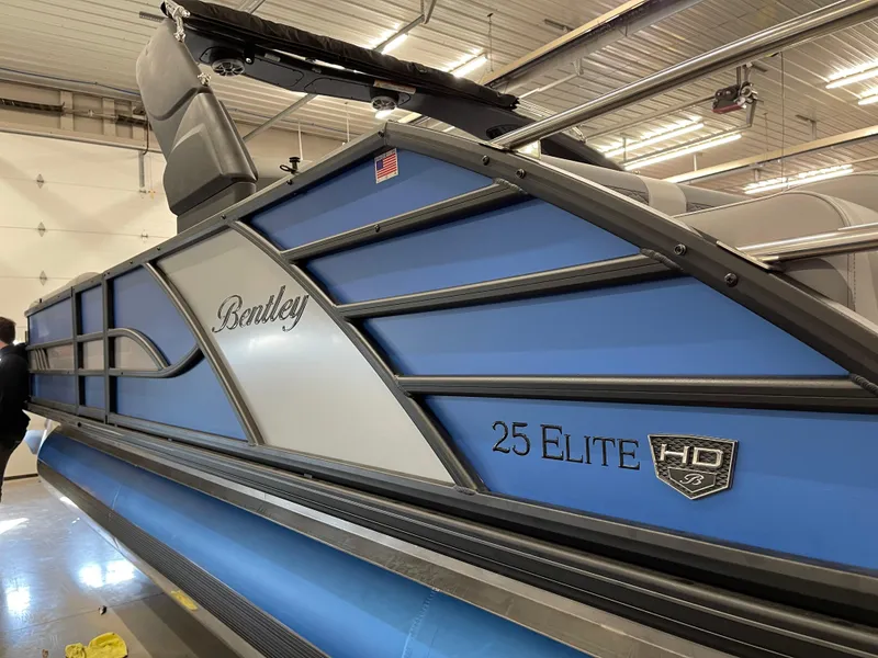 Slide: The Image of 2025 Bentley Pontoons Elite 253 Swingback Tower in a showroom, showcasing sleek blue design. - 5