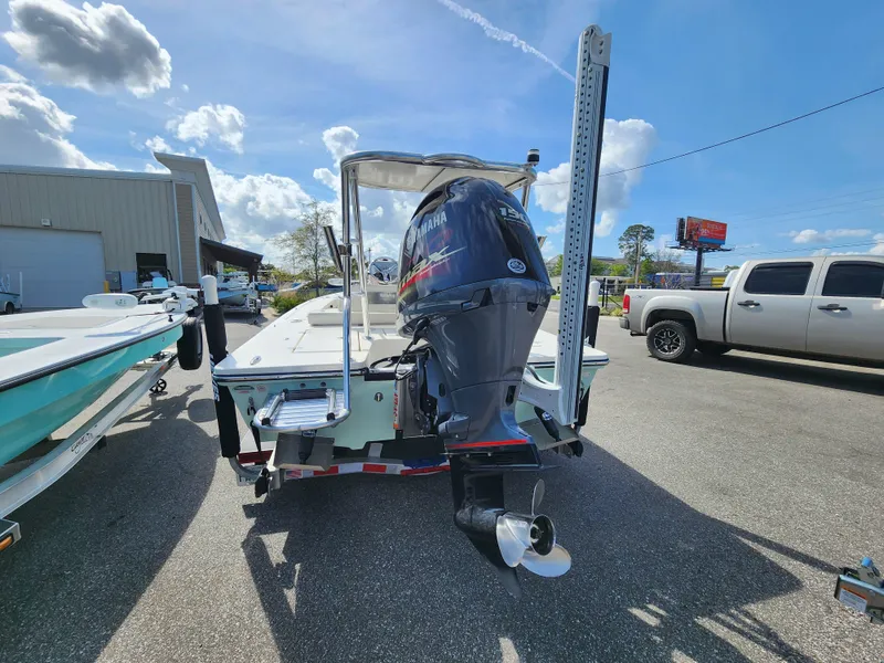 Slide: The Image of 2020 Hewes Redfisher 18 boat with outboard motor, parked outdoors under a sunny sky. - 2