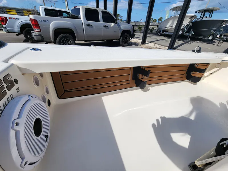 Slide: The Image of 2020 Hewes Redfisher 18 boat interior with speaker and storage, parked near trucks. - 6