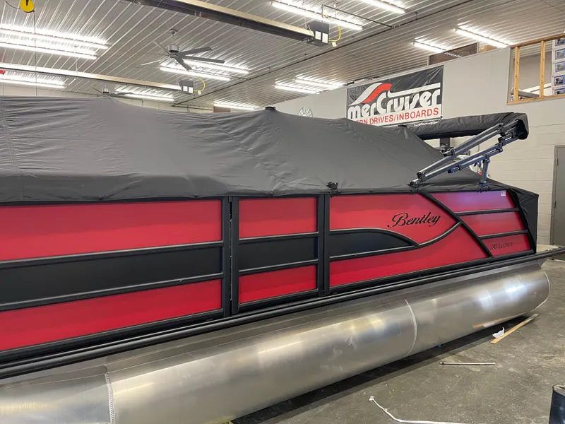 Slide: The Image of 2025 Bentley Pontoons Legacy 200 Swingback, red and black design, covered in a showroom. - 3