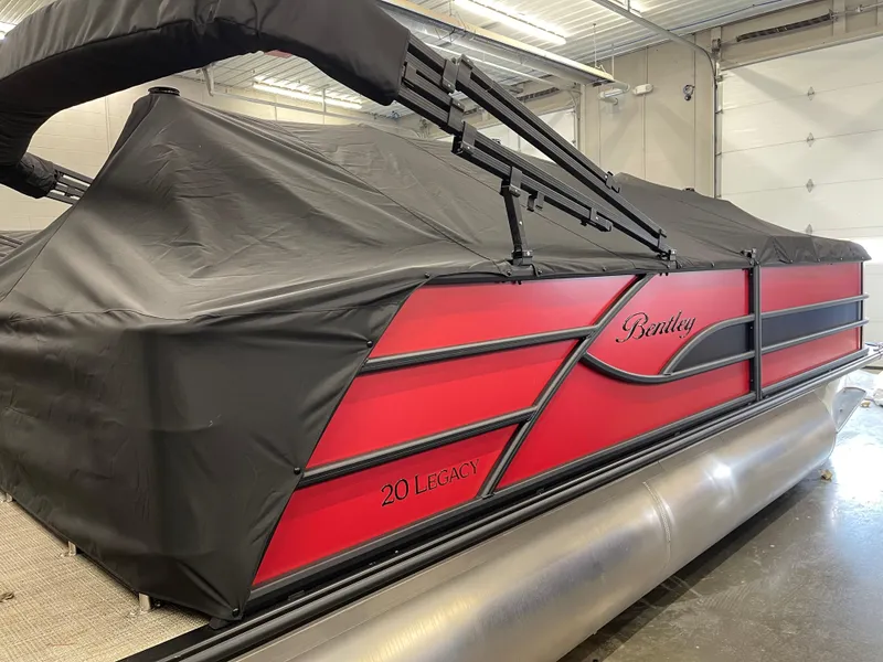Slide: The Image of 2025 Bentley Pontoons Legacy 200 Swingback with black cover in a garage setting. - 6