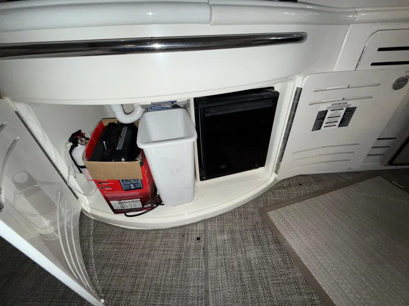 Slide: The Image of Storage compartment on a 2000 Sea Ray 510 Sundancer boat, featuring a fire extinguisher and trash bin. - 8