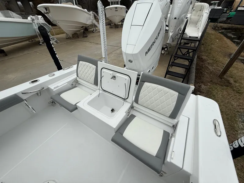 Slide: The Image of 2025 Everglades 253 Center Console boat with dual seats and storage, docked near other boats. - 9