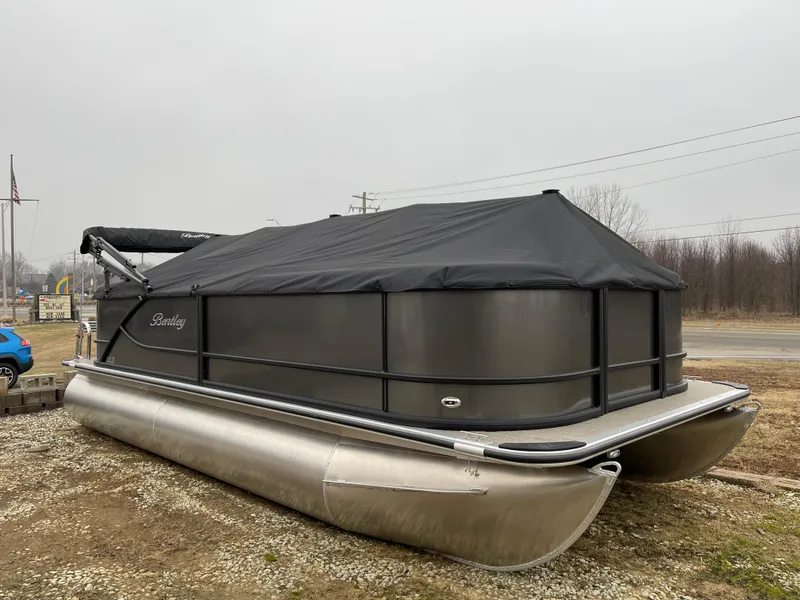 Slide: The Image of 2025 Bentley Pontoons LE 200 CW covered, parked on gravel lot. - 2