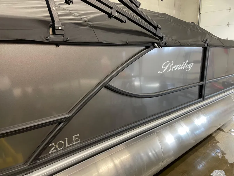 Slide: The Image of 2025 Bentley Pontoons LE 200 CW, sleek design, covered, side view in a garage. - 5