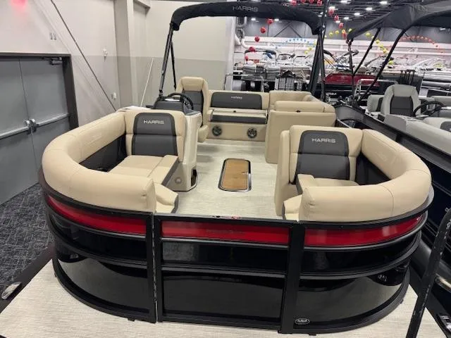 Slide: The Image of 2025 Harris Cruiser 210 pontoon boat with beige seating and black accents in showroom. - 2