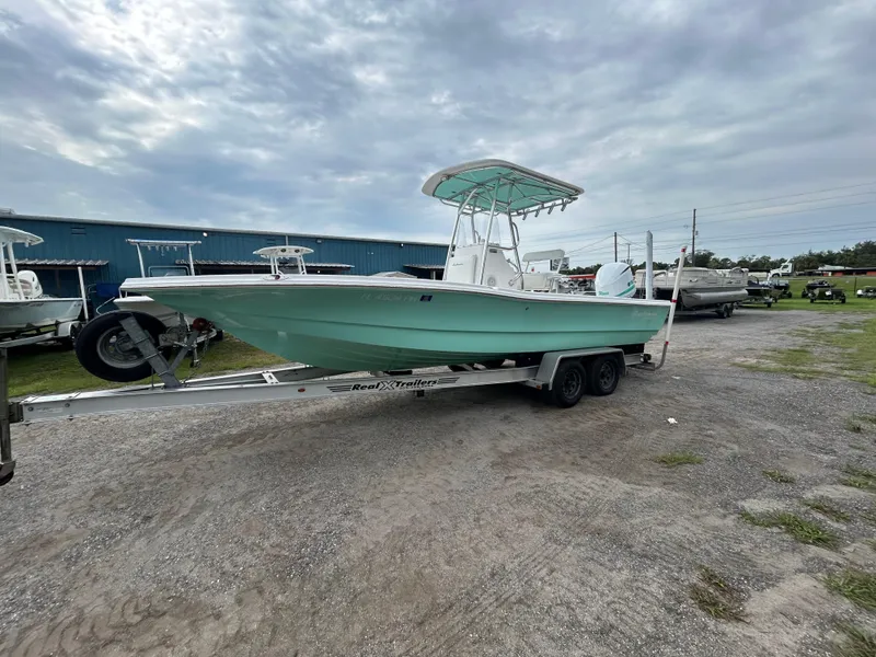 Slide: The Image of 2012 SeaHunter 24 Bay boat on trailer, parked outdoors under cloudy sky. - 1