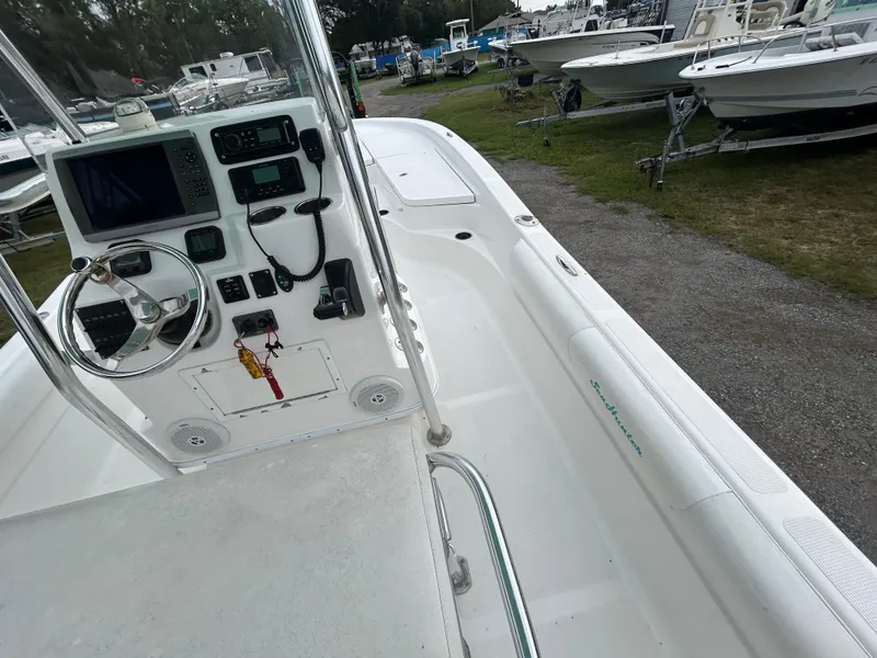 Slide: The Image of 2012 SeaHunter 24 Bay boat interior with steering console and electronics, parked among other boats. - 10