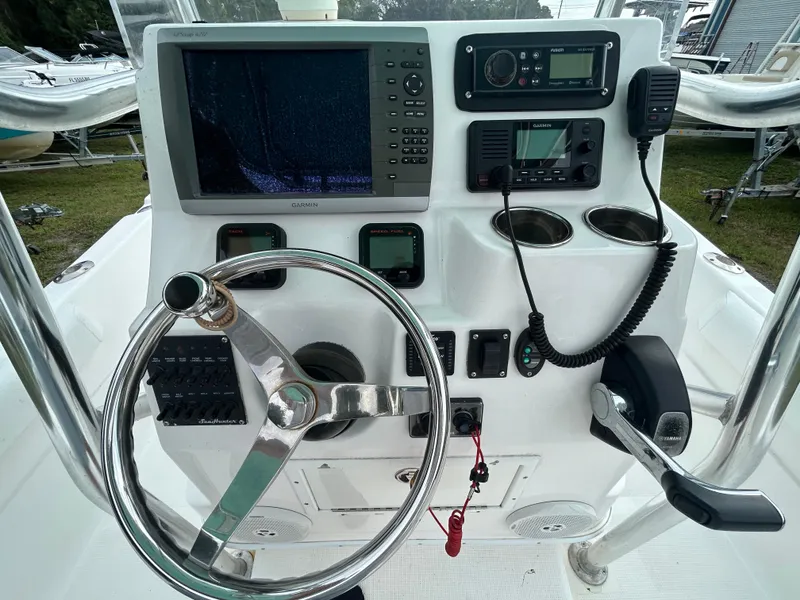 Slide: The Image of Control panel of a 2012 SeaHunter 24 Bay boat with steering wheel and electronics. - 12