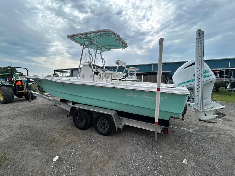 Slide: The Image of 2012 SeaHunter 24 Bay boat on trailer, light blue hull, parked outdoors. - 2