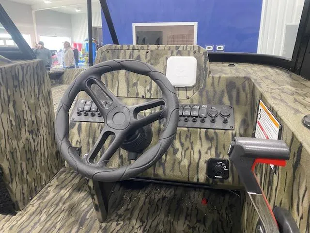 Slide: The Image of 2025 SeaArk Protege boat dashboard with camo design and steering wheel. - 7