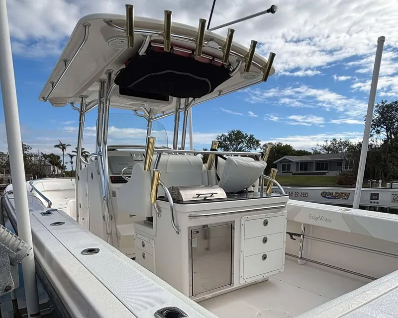Slide: The Image of 2012 Edgewater 318CC boat with center console, rod holders, and storage compartments under a cloudy sky. - 12