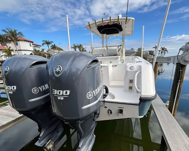 Slide: The Image of 2012 Edgewater 318CC boat with twin Yamaha 300 V6 engines docked by palm trees. - 21