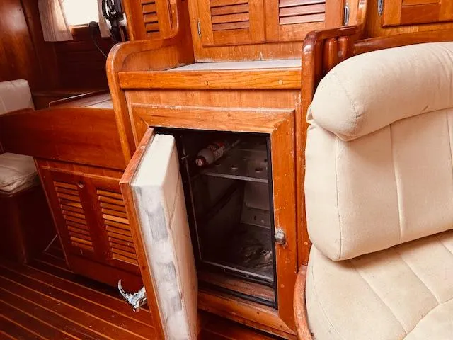 Slide: The Image of 1990 Bristol 47.7 yacht interior with open wooden cabinet and beige seating. - 13