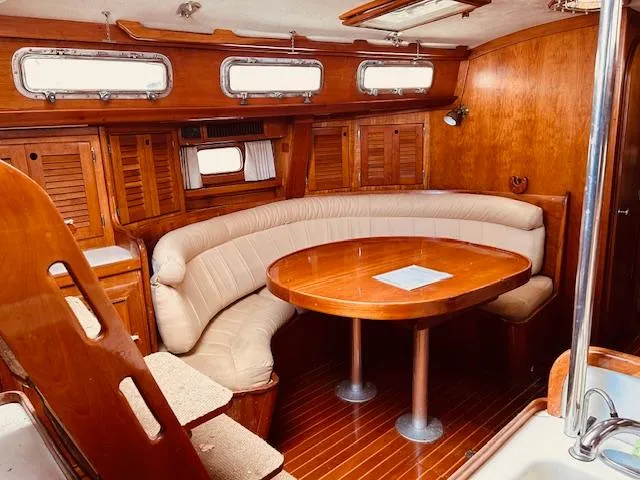 Slide: The Image of 1990 Bristol 47.7 yacht interior with wooden furnishings and curved seating area. - 2