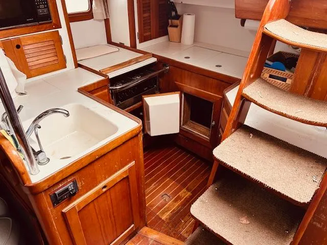 Slide: The Image of 1990 Bristol 47.7 yacht interior with wooden cabinetry and compact kitchen area. - 7