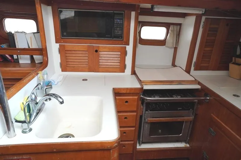 Slide: The Image of 1990 Bristol 47.7 yacht kitchen with sink, stove, and microwave in wooden cabinetry. - 8