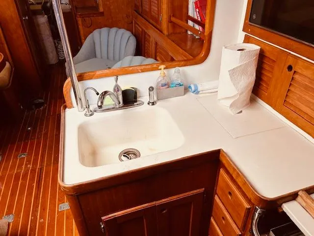 Slide: The Image of 1990 Bristol 47.7 yacht kitchen with sink, wooden cabinets, and paper towel holder. - 9