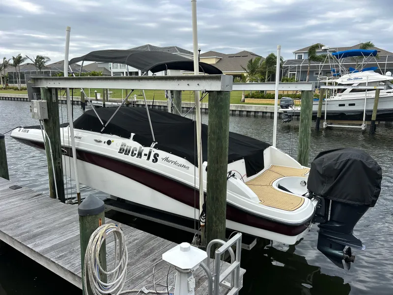 Slide: The Image of 2019 Hurricane SunDeck 2690 OB boat docked with cover, in a marina setting. - 4