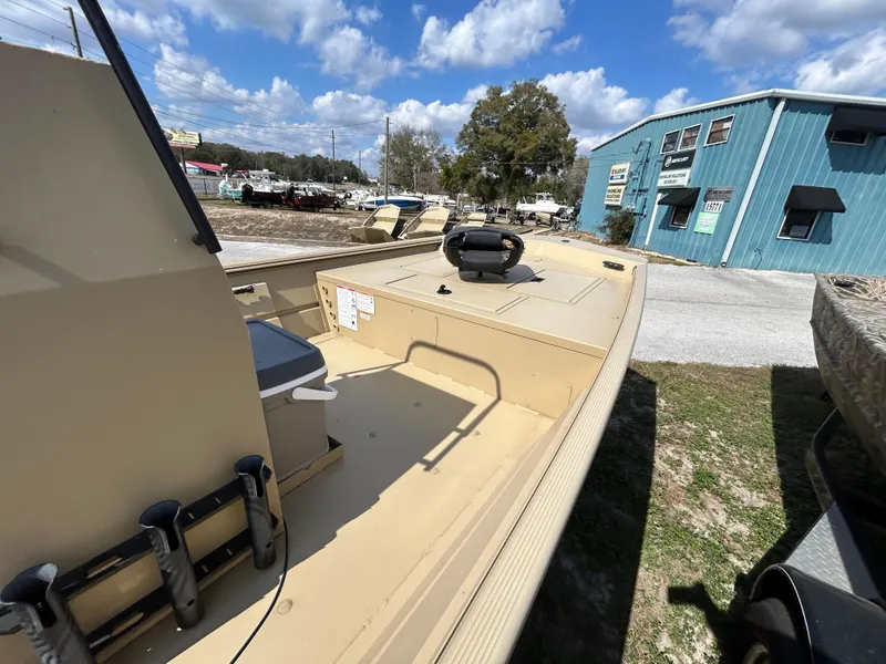 Slide: The Image of 2024 Crestliner 1860 Retriever CC Tunnel boat, beige deck, outdoor display, blue building background. - 5