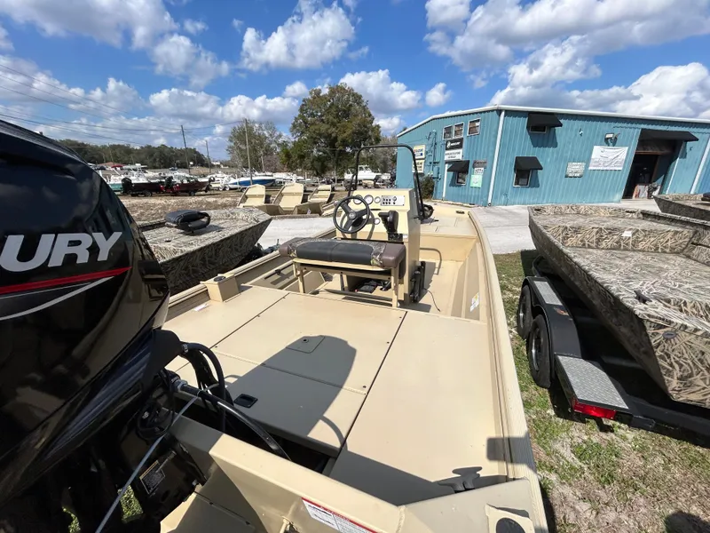Slide: The Image of 2024 Crestliner 1860 Retriever CC Tunnel boat, beige, parked outdoors near a blue building. - 8