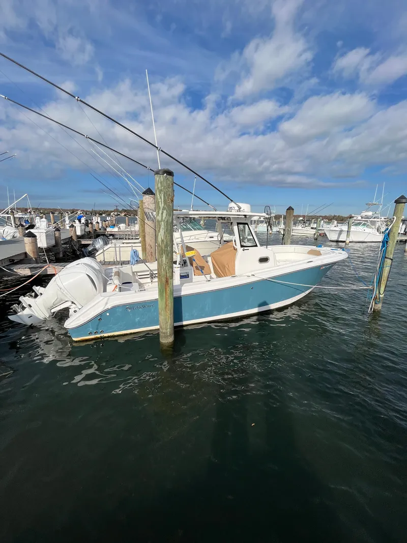Slide: The Image of 2022 Edgewater 285CC boat docked at marina under blue sky. - 1