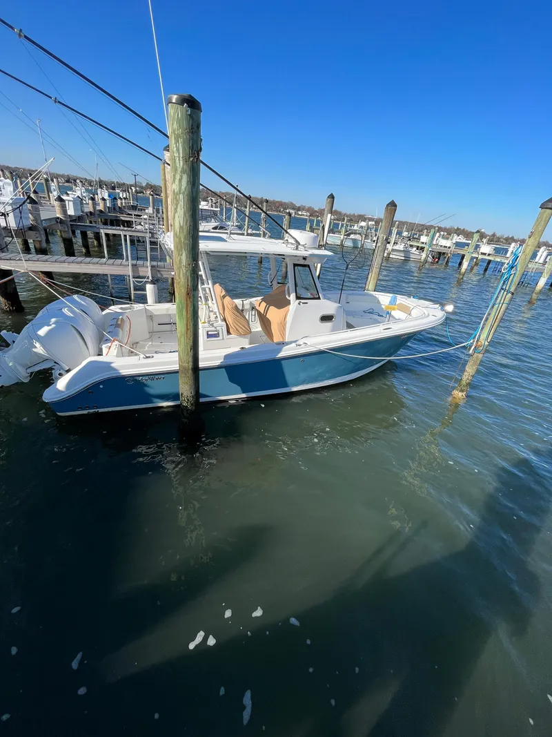 Slide: The Image of 2022 Edgewater 285CC boat docked in a marina under clear blue skies. - 12