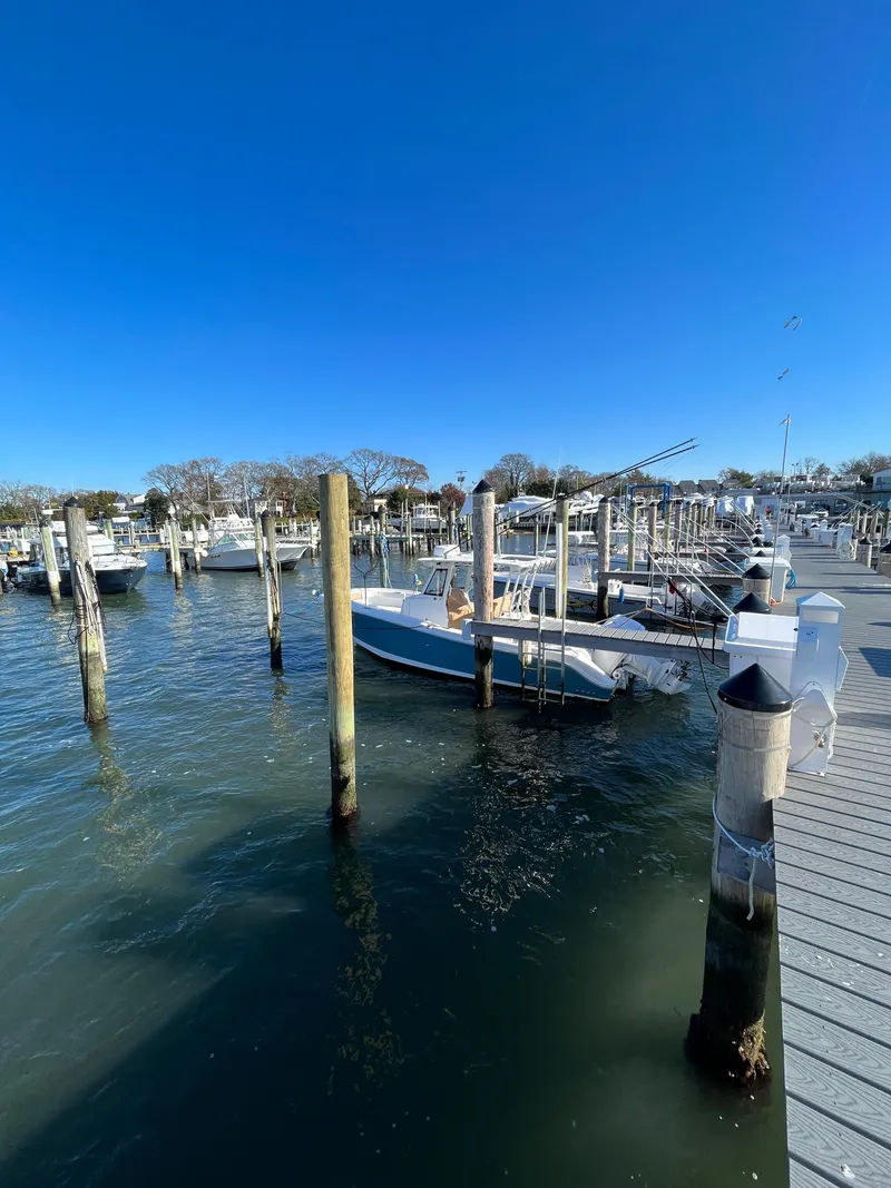 Slide: The Image of 2022 Edgewater 285CC boat docked at marina under clear blue sky. - 14