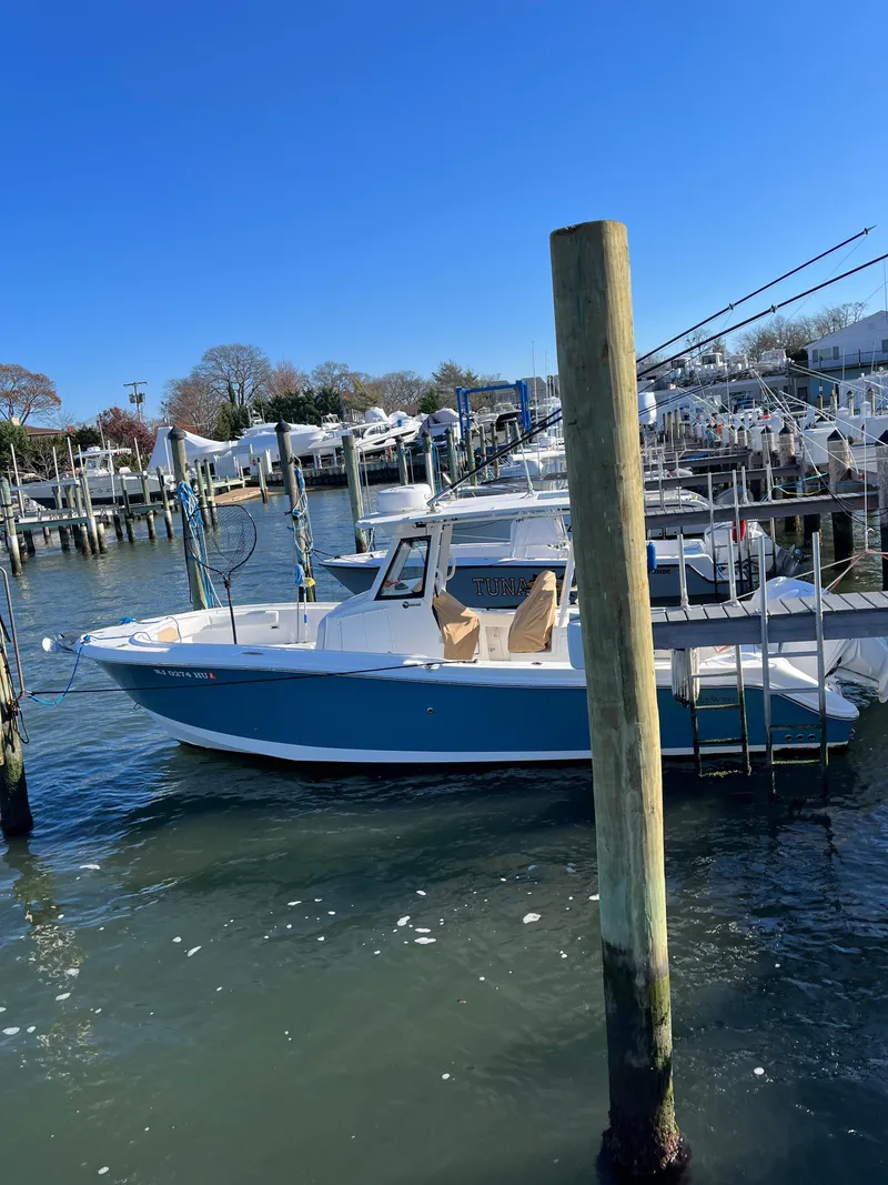 Slide: The Image of 2022 Edgewater 285CC boat docked in a marina on a sunny day. - 16